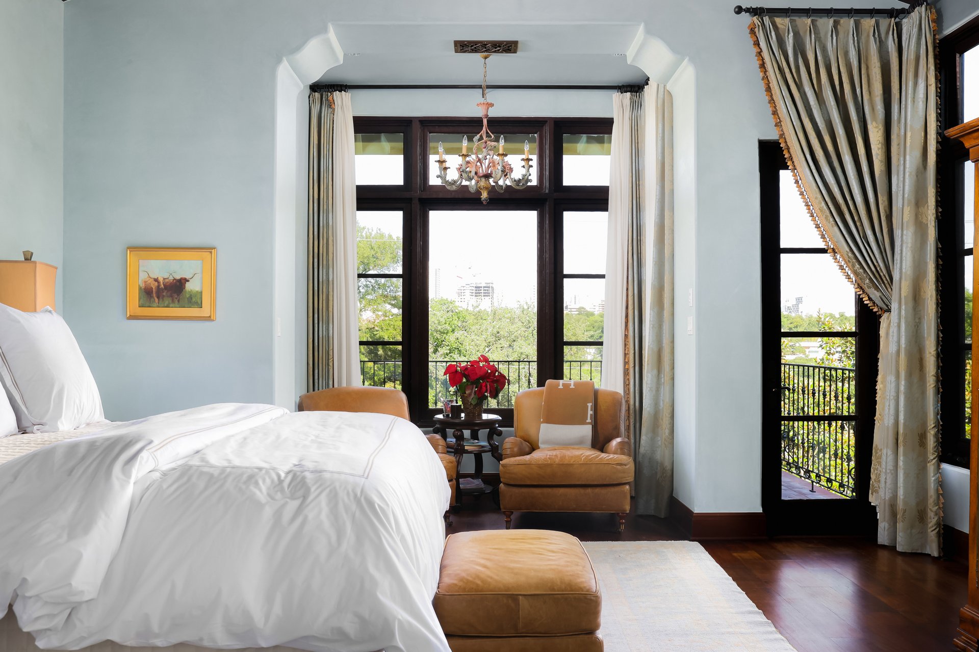 Primary bedroom with skyline view, French doors, and crystal chandelier