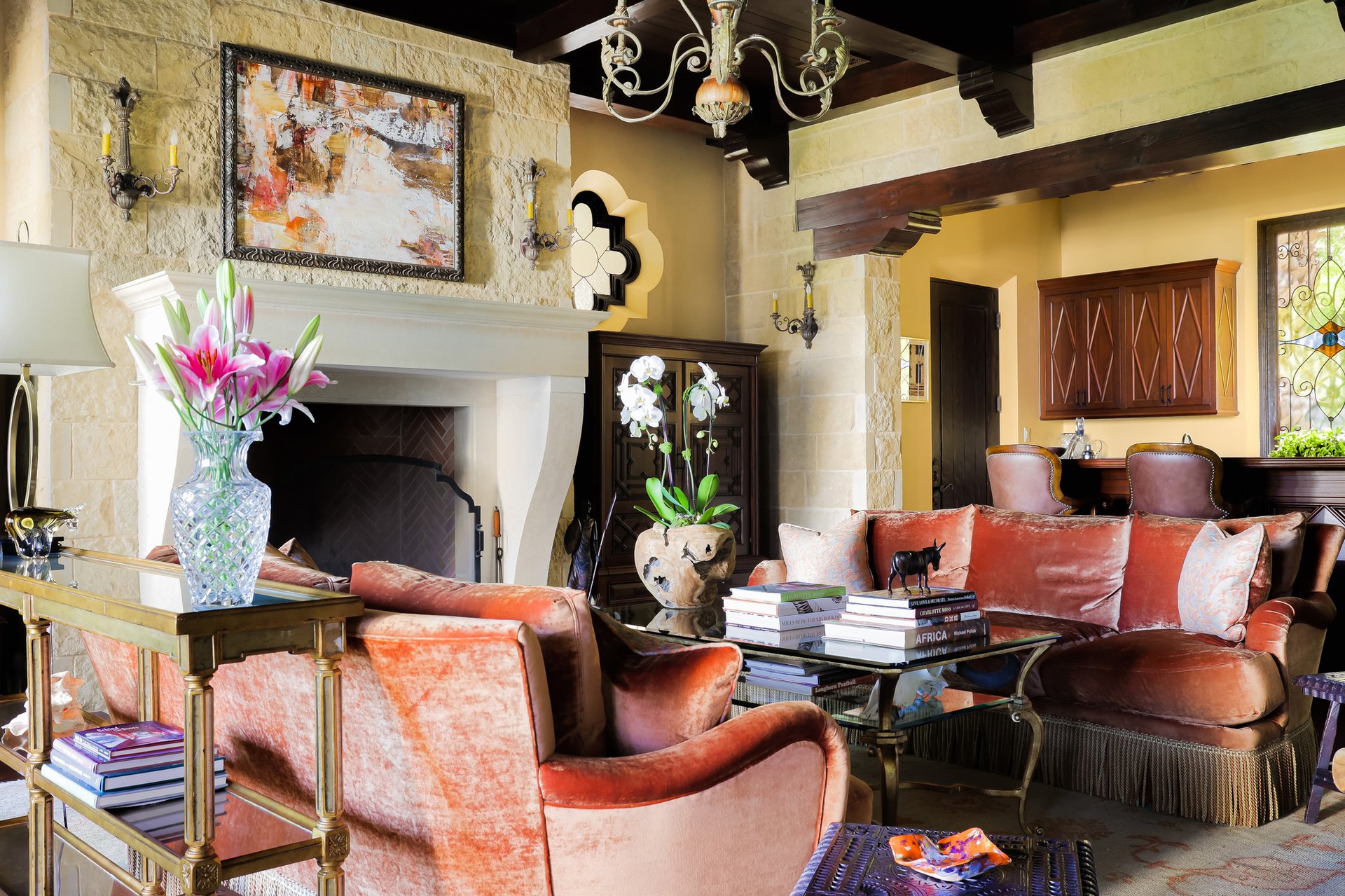 Living room with stone fireplace, velvet sofas, and chandelier